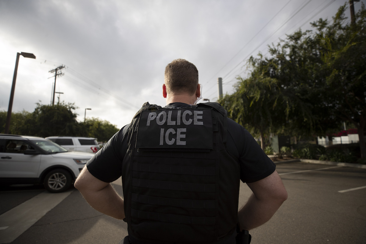 ICE agent with vest facing away from the camera