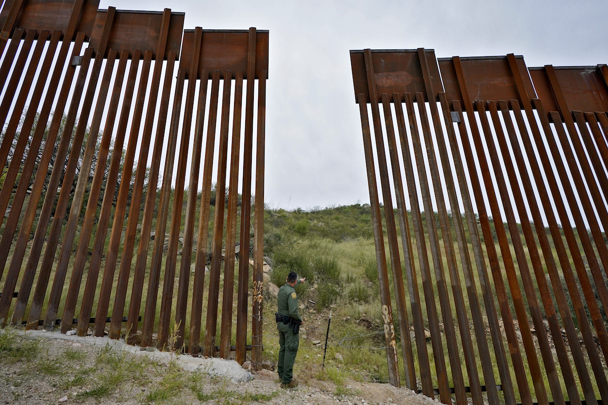 Photo of Border Patrol agent standing in a gap in the border wall Spet. 2022