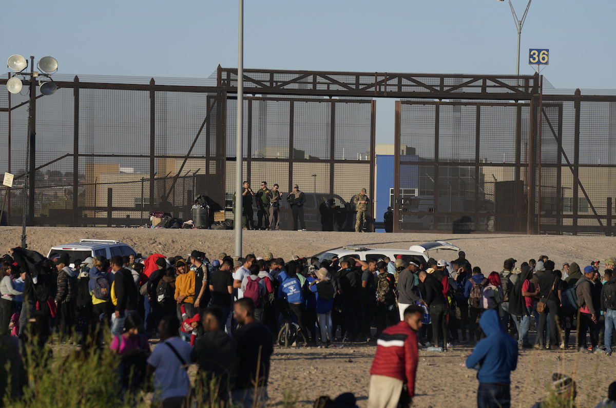 Migrant crowd outside of border fence guarded by border patrol