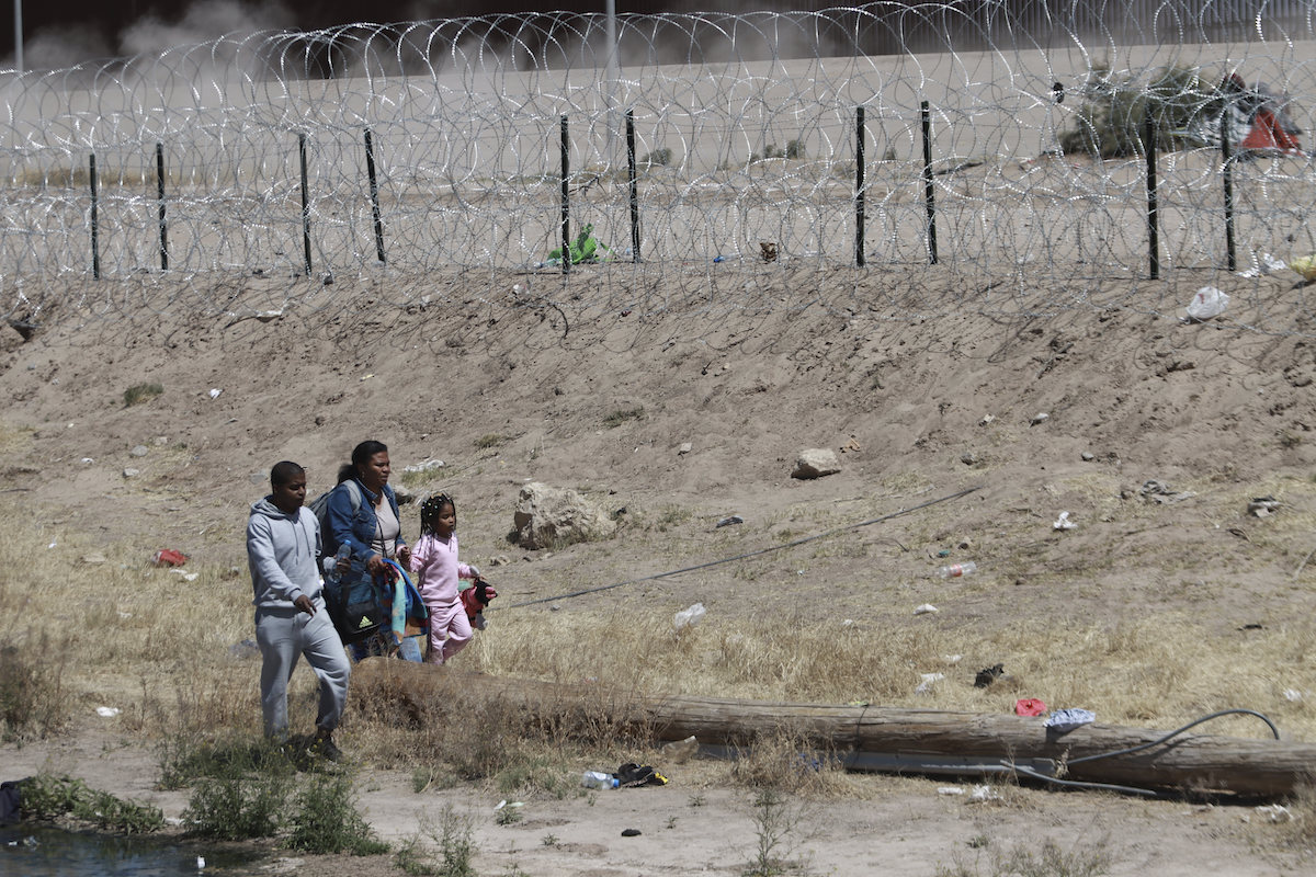 Mother and two children walking by a border fence
