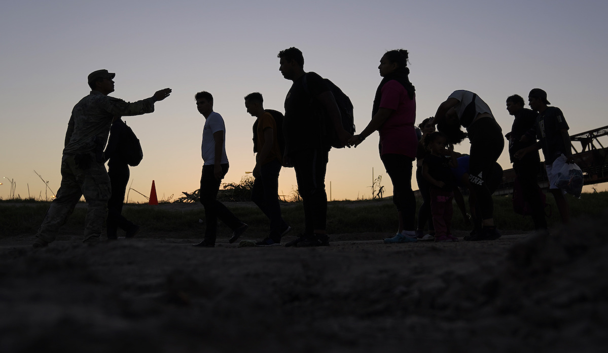 Silhouette migrants at border directed by border patrol