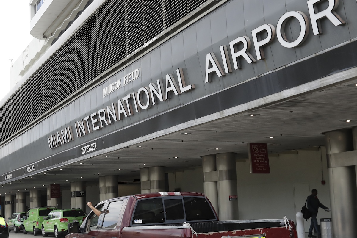 Vehicles pass the entrance to Miami International Airport in Miami, 5-12-2020