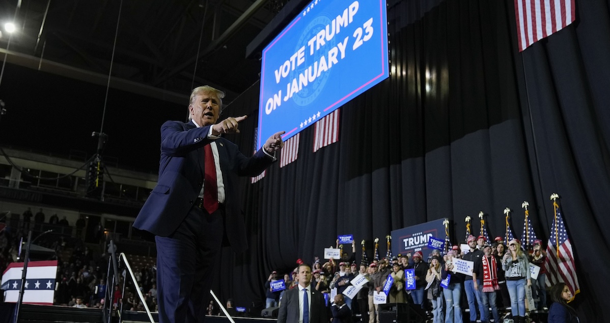 Trump at Manchester rally Jan. 20, 2024 pointing with screen for voting behing