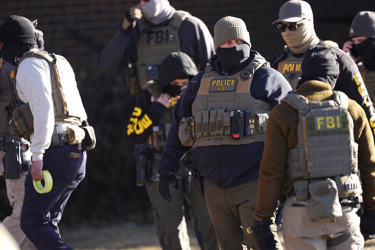 Law officials enter an apartment complex during a raid 02-05-2025