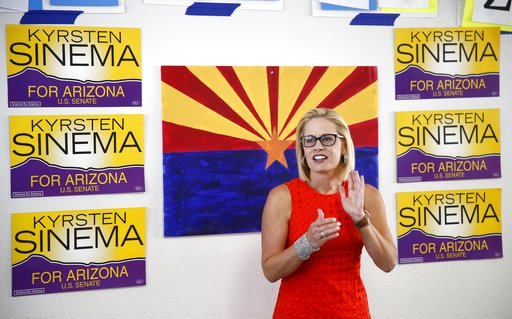 Sinema in front of campaign signs