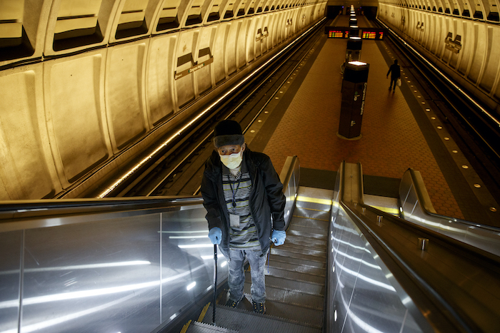 man with mask rides escalator