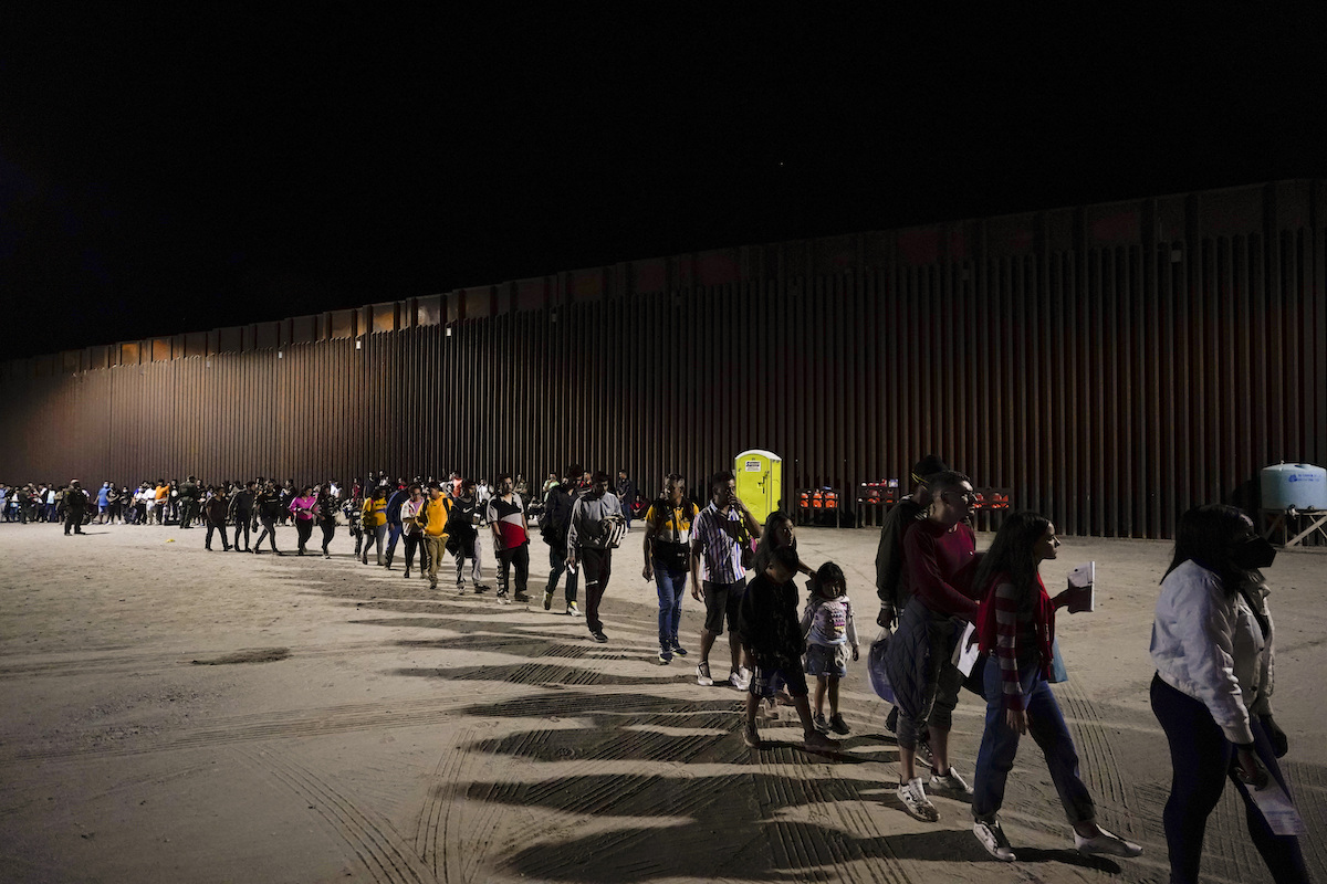 Photo of southern border and immigrants lining up after crossing into Arizona
