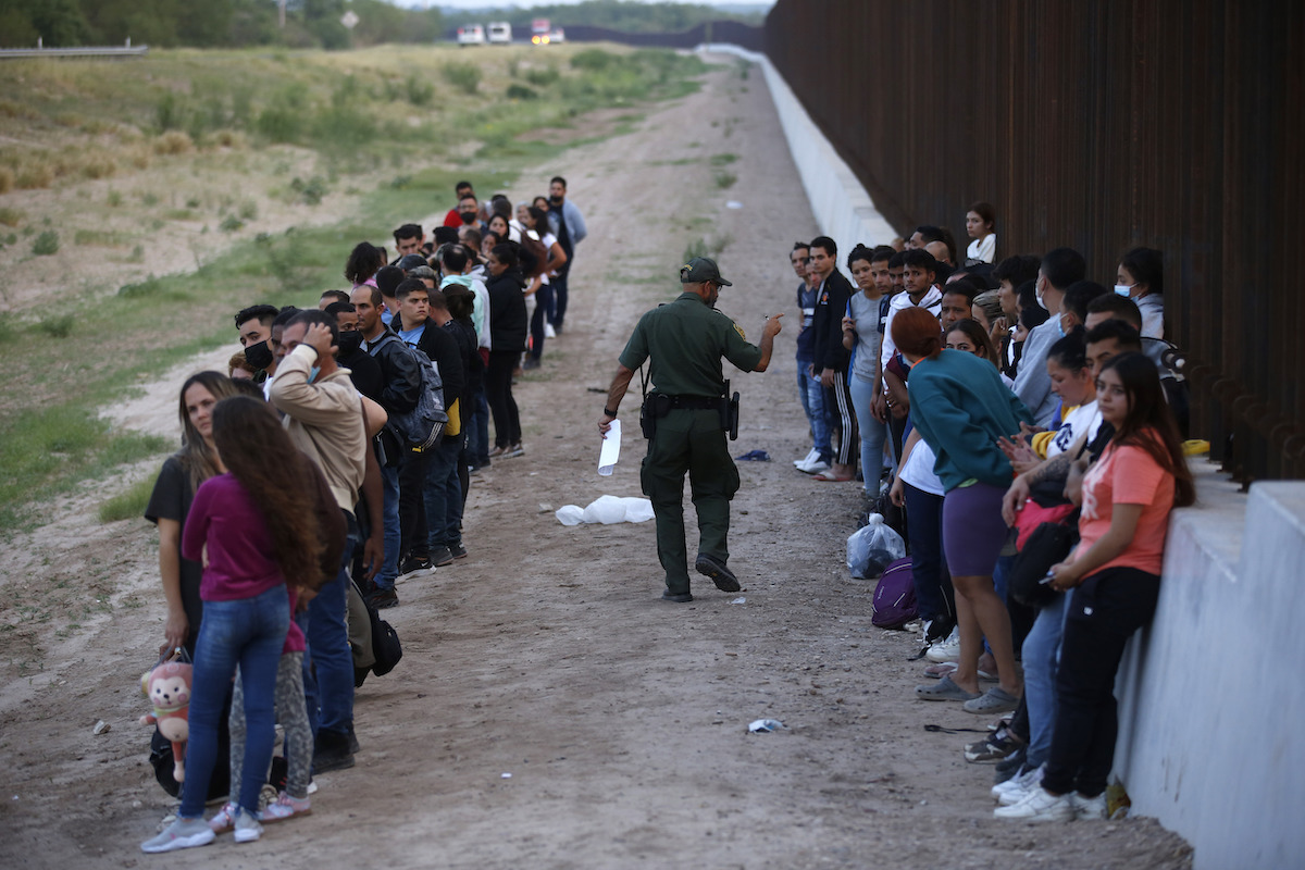 Two rows of immigrants at border with CBP officer