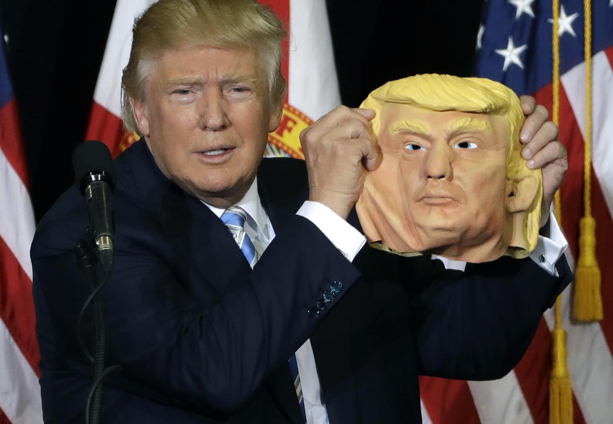Trump holds up mask
