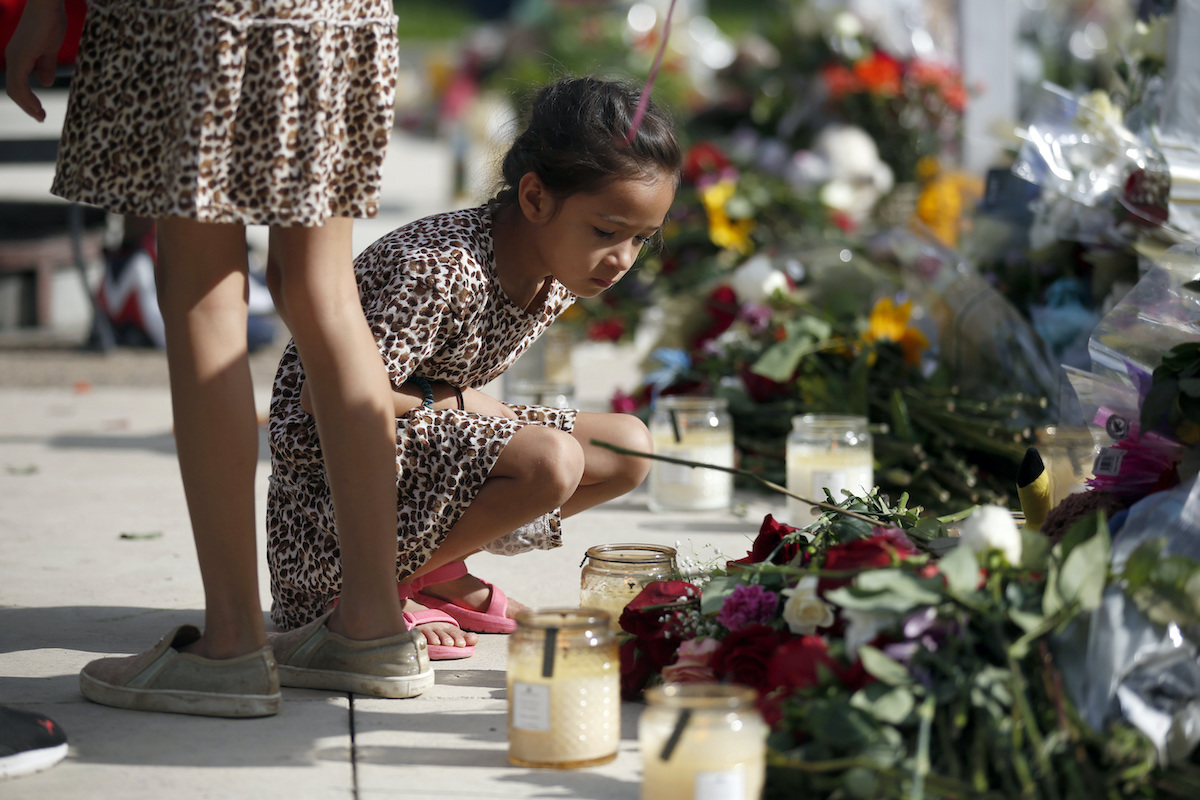 A child in a leopard print dress looks at a memorial site for the victims killed in the May 24 shooting at Robb Elementary School