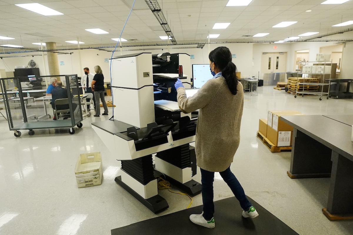 Maricopa election worker with ballot and machine 8-3-22