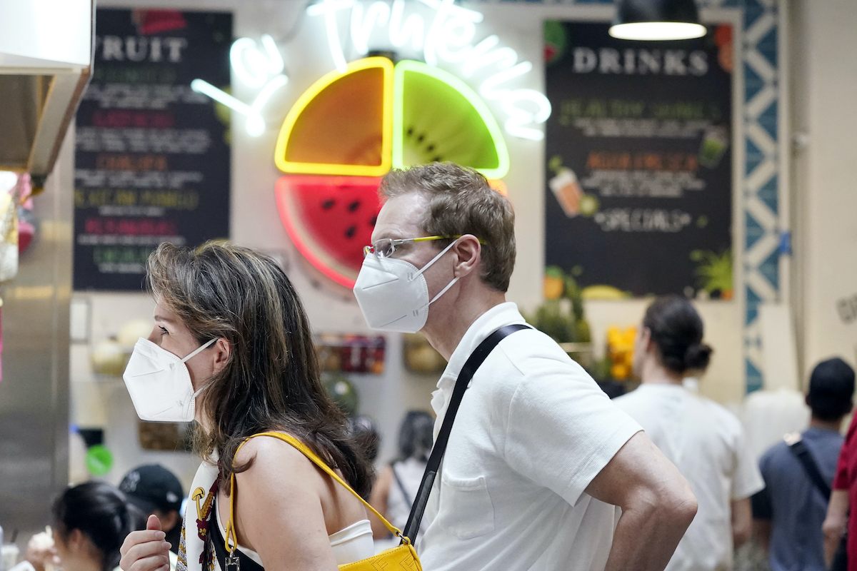 Masked patrons wait to order at a food stand inside in Los Angeles on July 13