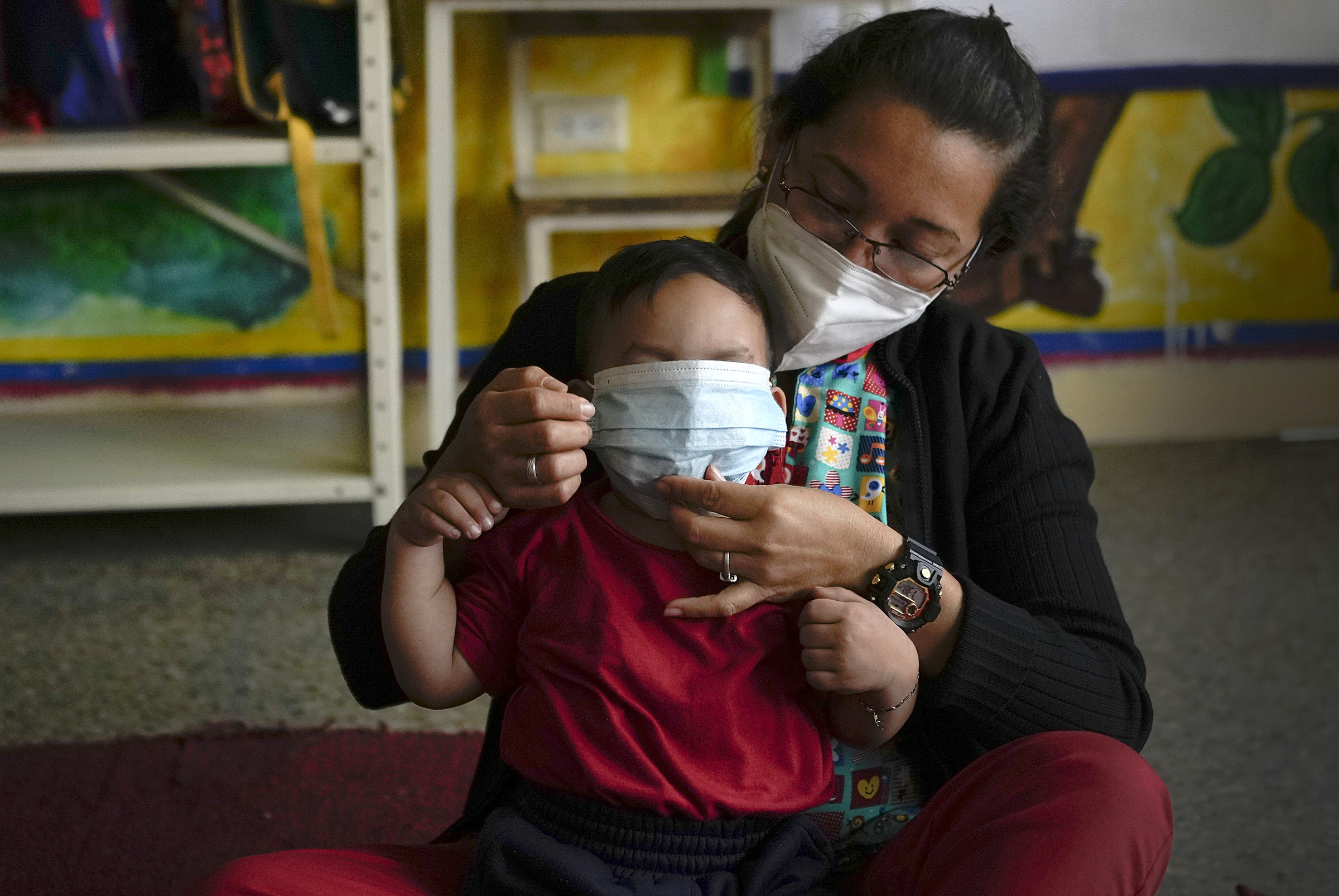 Teacher helps child with mask