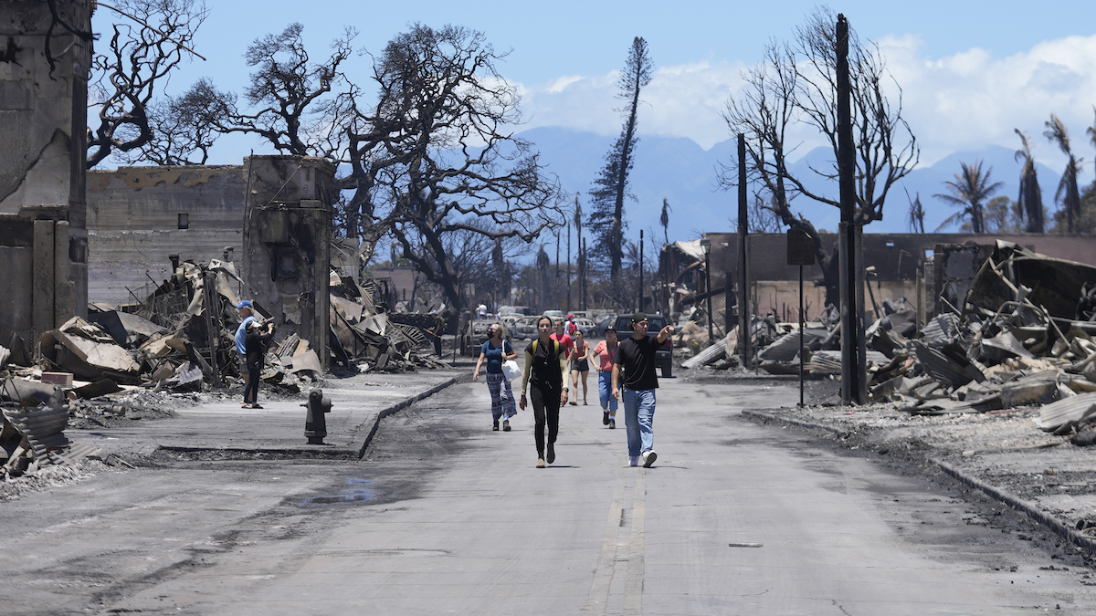 People walk Main Street past wildfire damage in Lahaina, Hawaii, 8-11-2023