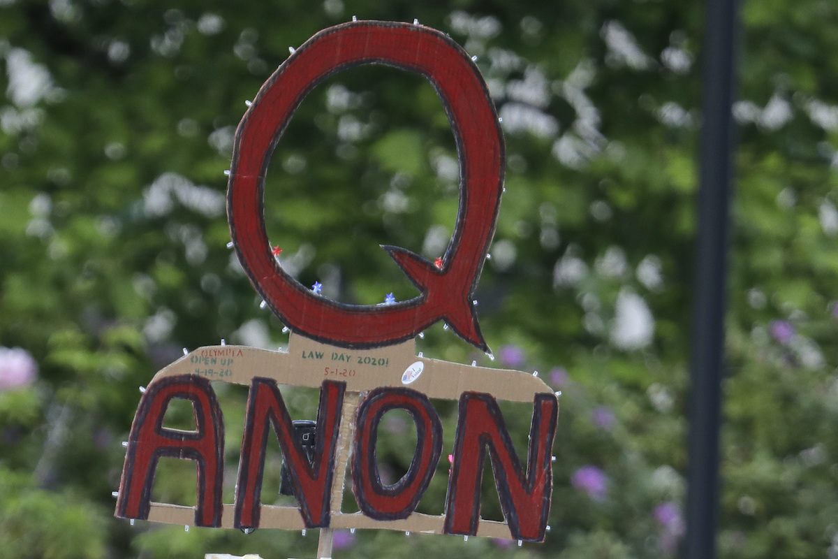A QAnon protester holds up a cardboard Q.