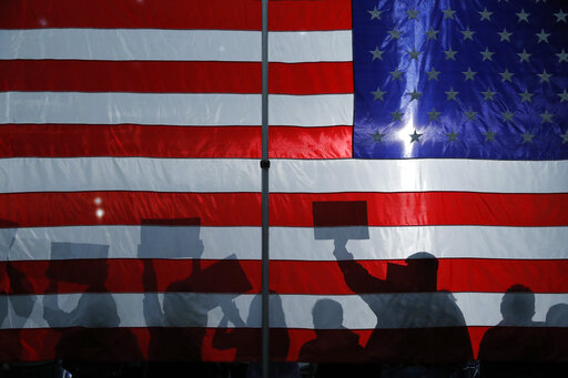 people cheer behind flag at Sanders rally Iowa
