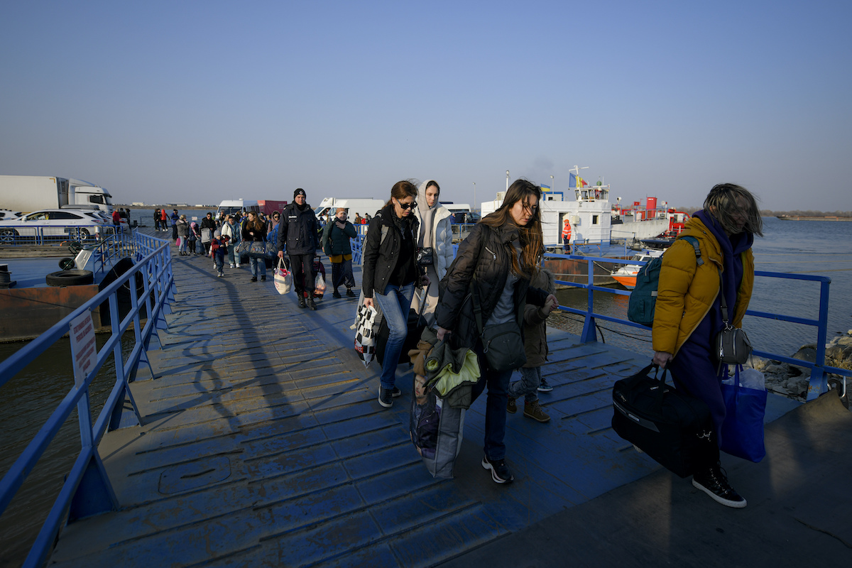 Ukrainian refugees walk after crossing into Romania by ferry on March 24, 2022