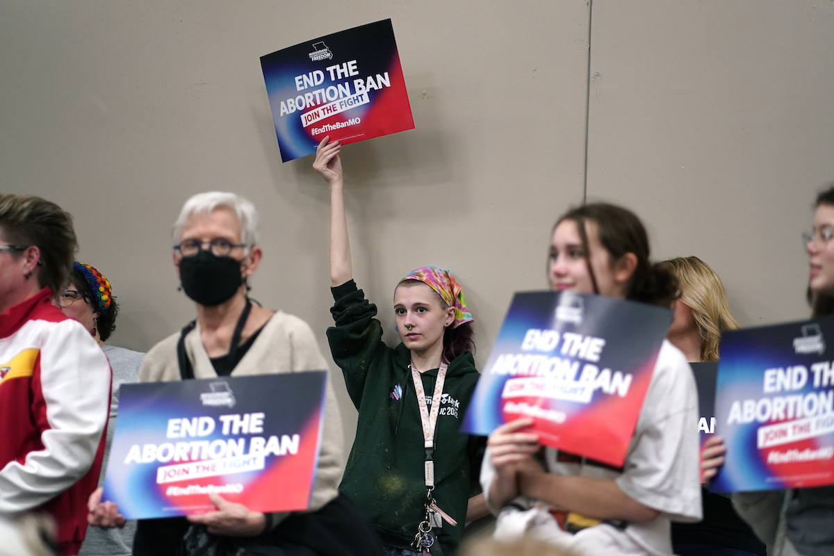 Women hold up "end abortion ban" signs in Missouri