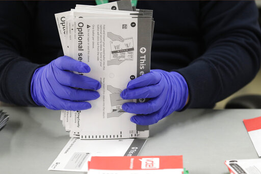 poll worker with ballot and gloves