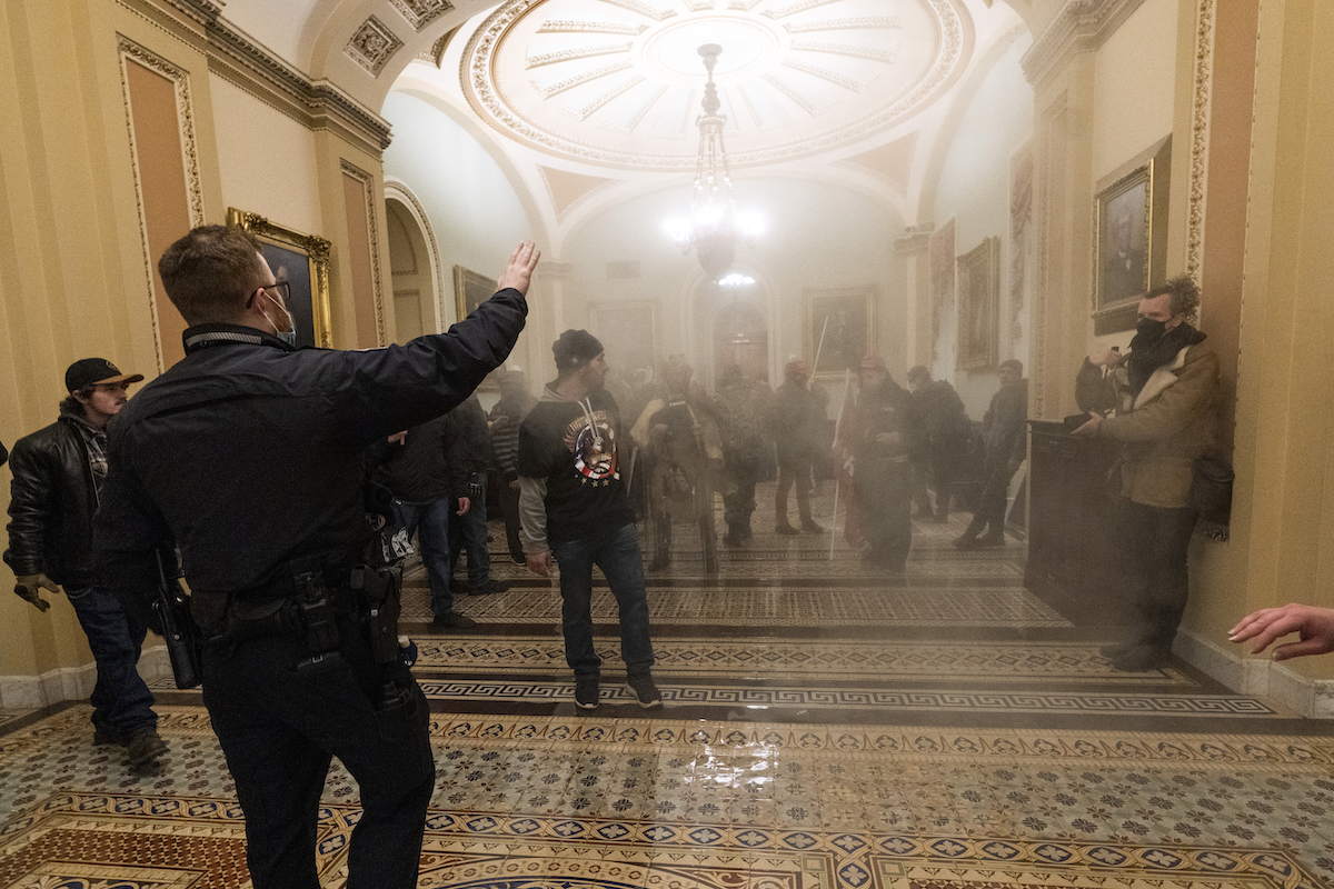 Smoke fills the walkway outside the Senate Chamber as rioters are confronted by U.S. Capitol Police officers Jan. 6, 2021