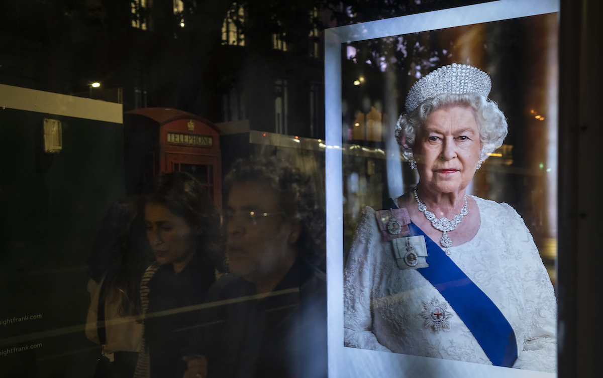 Image of Queen Elizabeth as people walk past