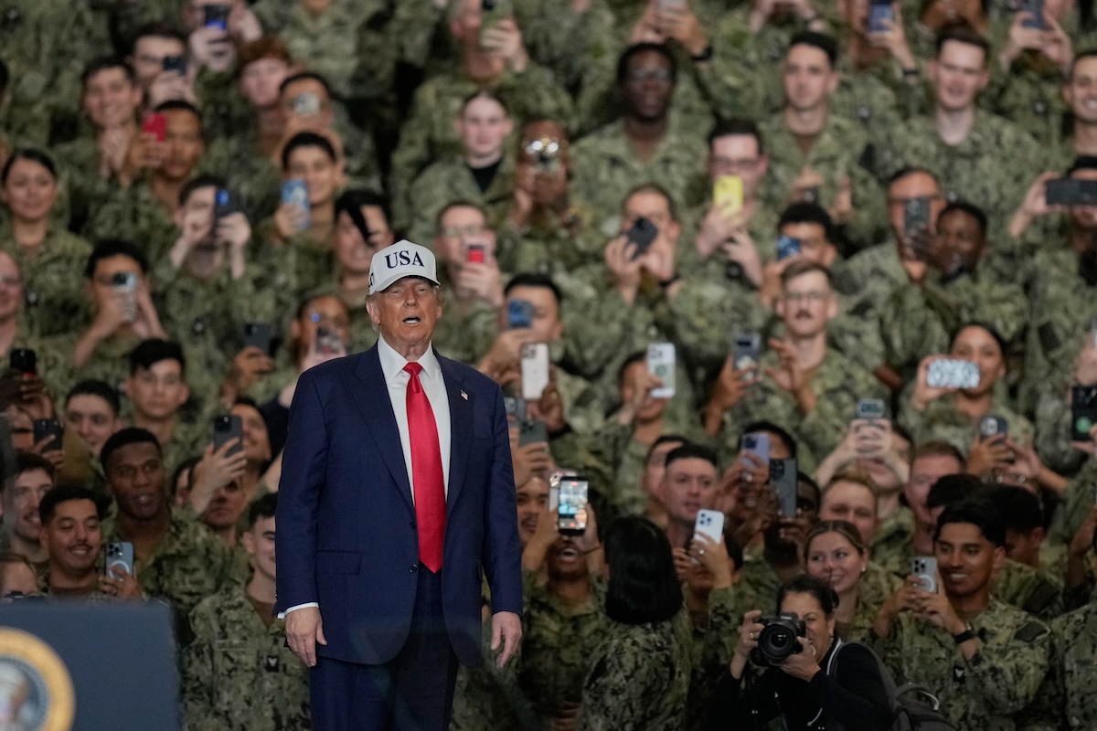 Trump on board Navy ship with seamen standing behind him