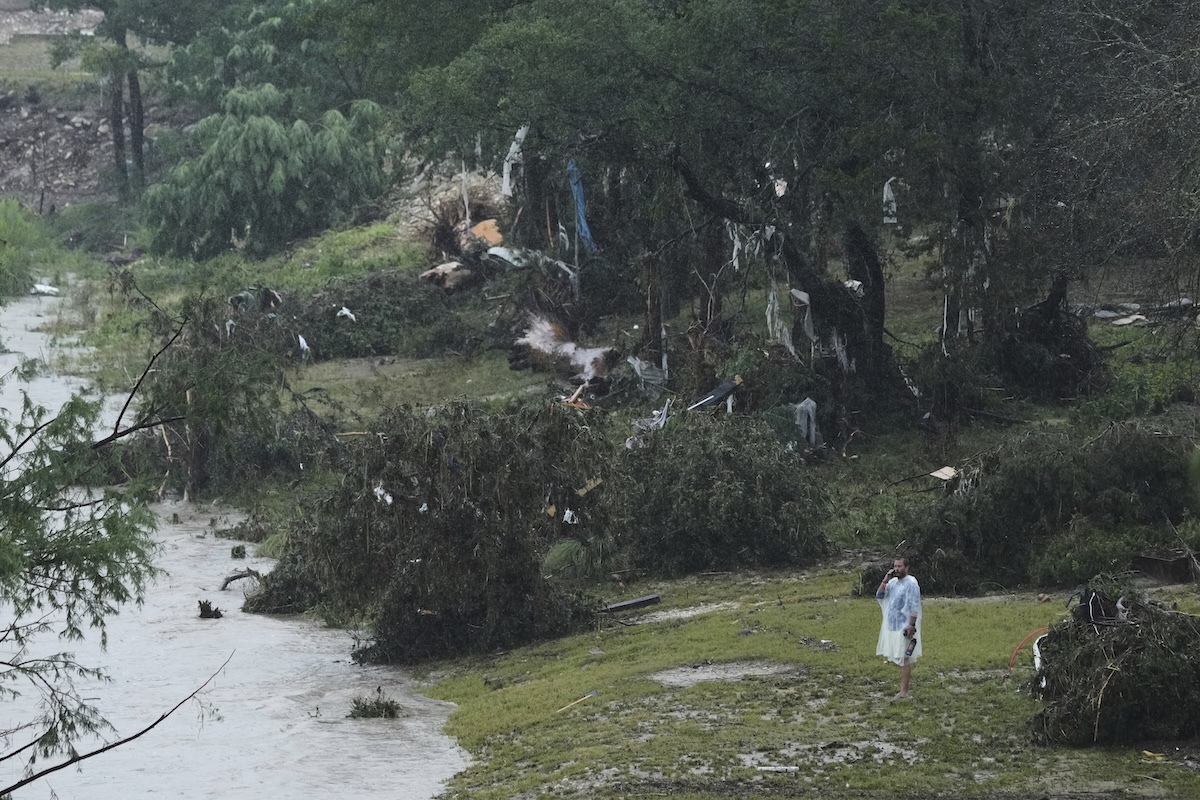 A man surveys damage left by a ranging Guadalupe River 07-04-2025