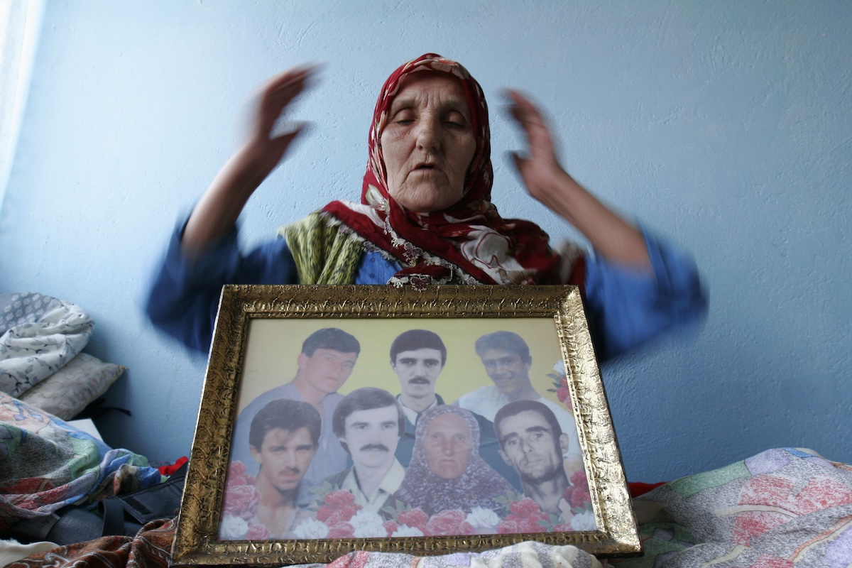 Bosnian muslim refugee displays photos of loved ones who were killed in 1995 2-25-2007