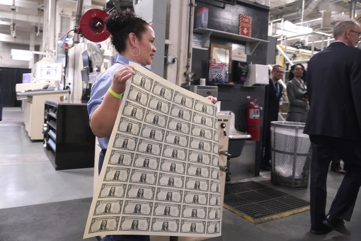 Worker carrying sheet of newly printed dollar bills