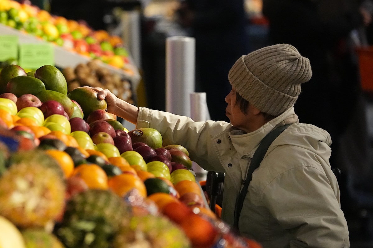 Shopper reaching for fruit at fruit stand