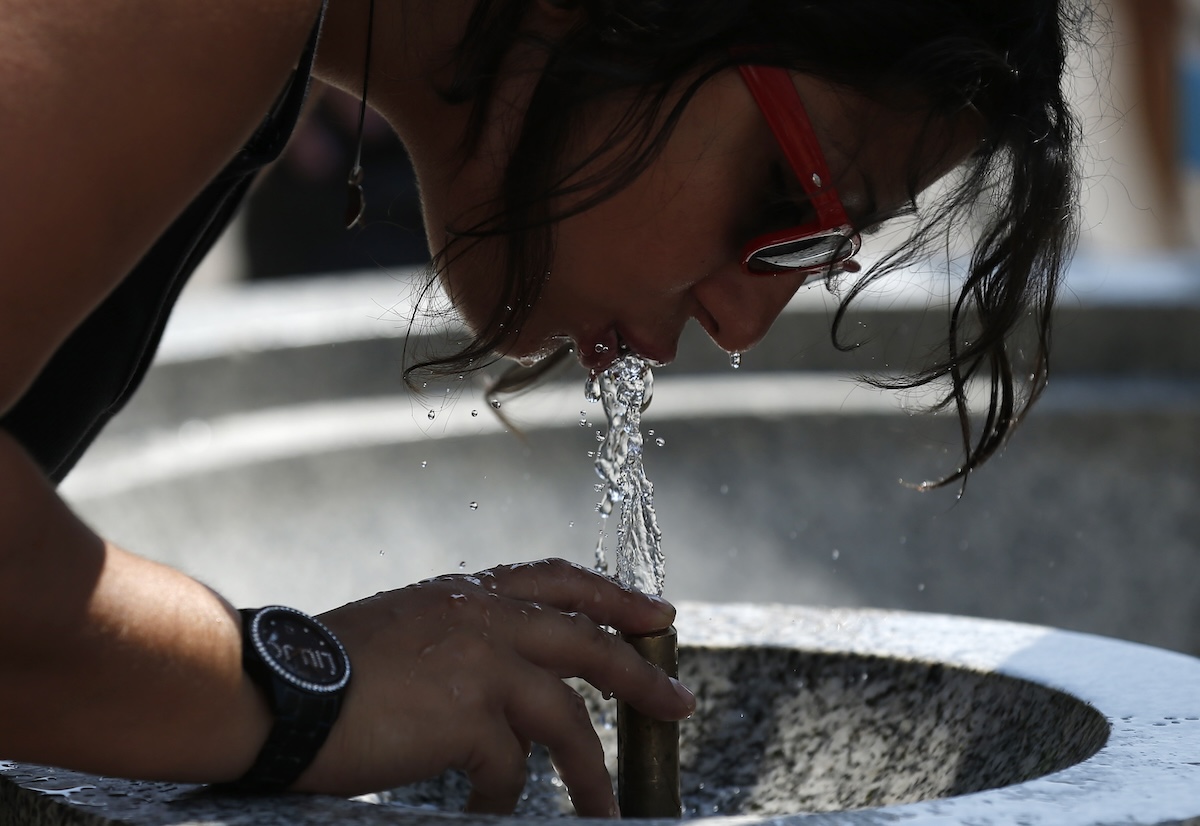 Woman drinking from water fountain in london