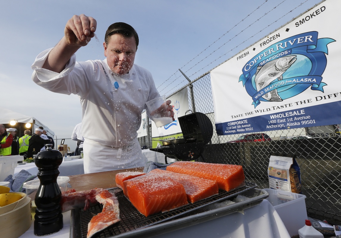 Chef sprinkles salt on cuts of salmon May 16, 2014